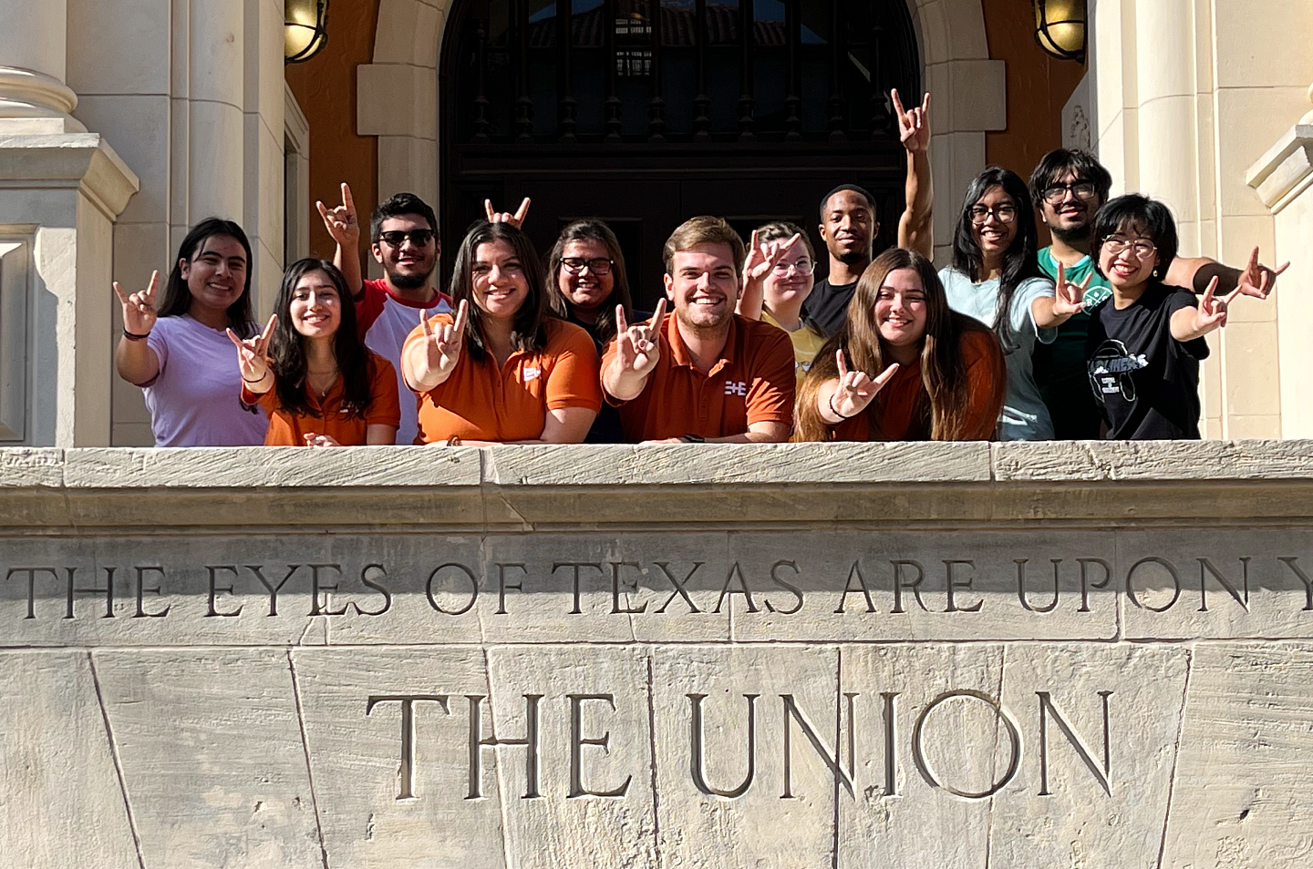 students posing with the hook'em handsign