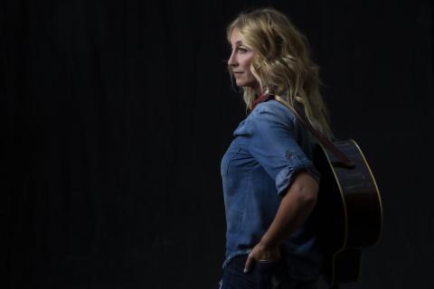 Woman in denim shirt with guitar on her back