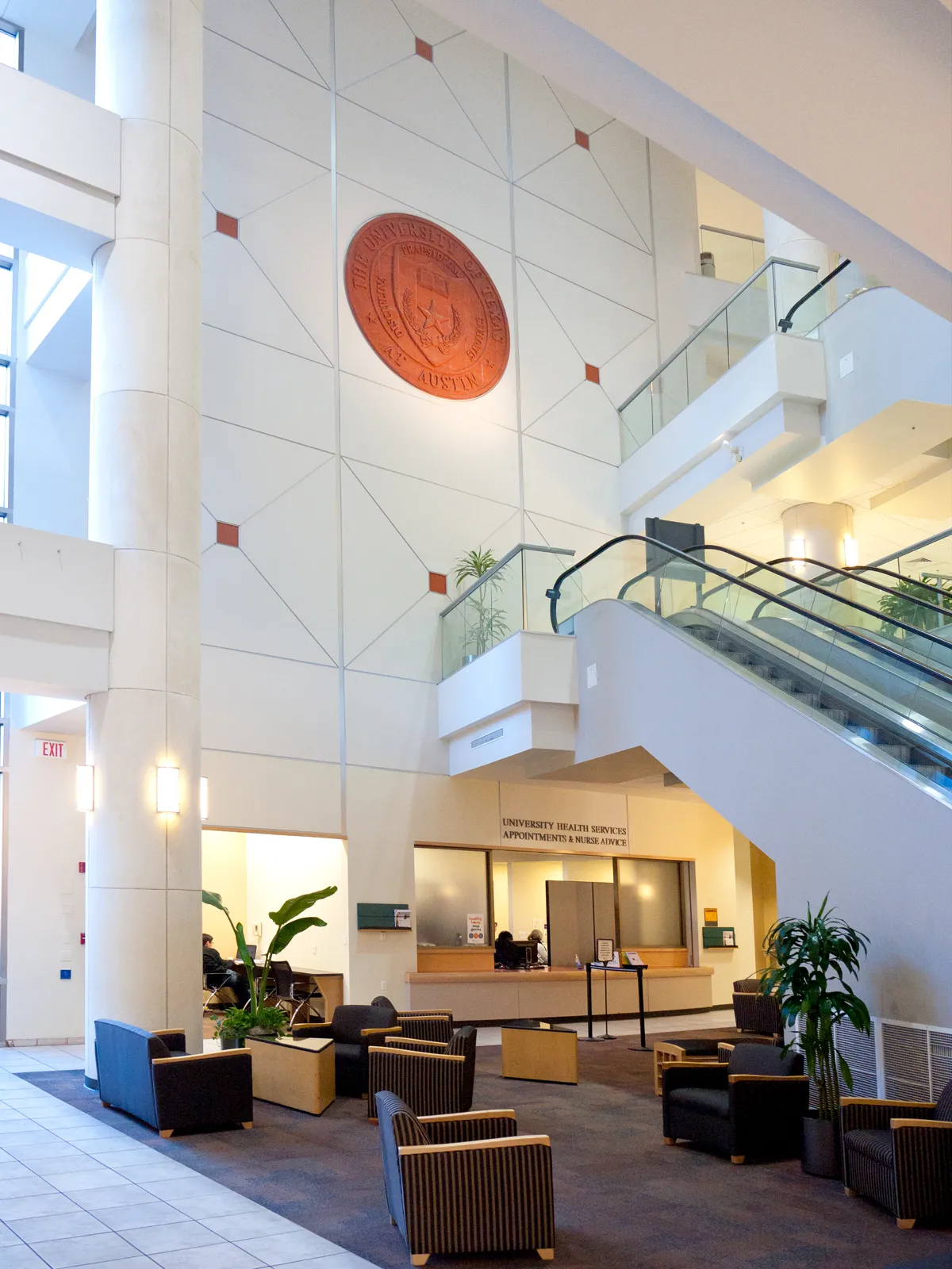 image of the lobby of the Student Services Building with the UT Austin seal above a set of escalators  