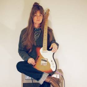 huey with guitar sits on amp